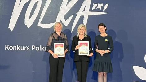 Kobiety stoją na scenie, trzymają w rękach dyplomy, pozują do zdjęcia