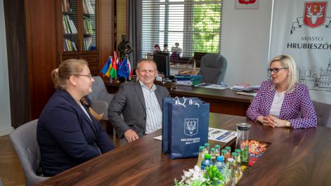Burmistrz oraz zawodniczka z trenerem siedzą przy stole, rozmawiają