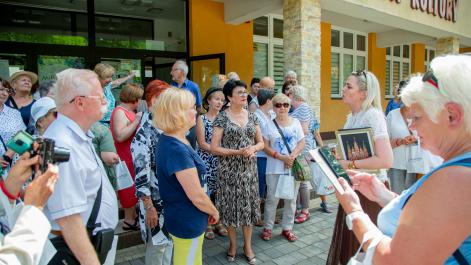 Seniorzy zebrali się na placu przed domem kultury, rozmawiają
