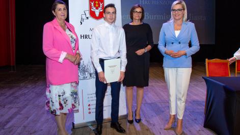 Kobiety oraz stypendysta pozują do zdjęcia, w tle widać roll-up z herbem miasta Hrubieszów