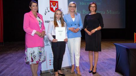 Kobiety oraz stypendystka pozują do zdjęcia, w tle widać roll-up z herbem miasta Hrubieszów