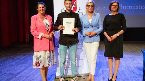 Kobiety oraz stypendysta pozują do zdjęcia, w tle widać roll-up z herbem miasta Hrubieszów