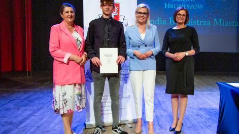 Kobiety oraz stypendysta pozują do zdjęcia, w tle widać roll-up z herbem miasta Hrubieszów