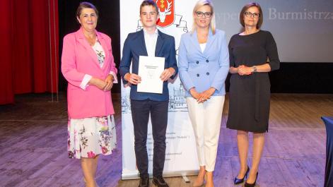 Kobiety oraz stypendysta pozują do zdjęcia, w tle widać roll-up z herbem miasta Hrubieszów