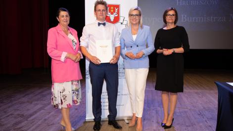 Kobiety oraz stypendysta pozują do zdjęcia, w tle widać roll-up z herbem miasta Hrubieszów
