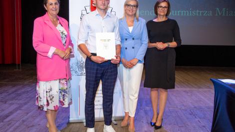 Kobiety oraz stypendysta pozują do zdjęcia, w tle widać roll-up z herbem miasta Hrubieszów