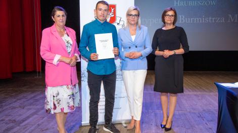 Kobiety oraz stypendysta pozują do zdjęcia, w tle widać roll-up z herbem miasta Hrubieszów