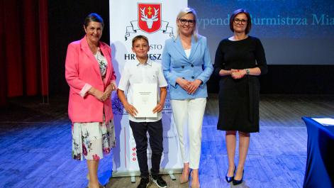 Kobiety oraz stypendysta pozują do zdjęcia, w tle widać roll-up z herbem miasta Hrubieszów