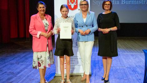 Kobiety oraz stypendystka pozują do zdjęcia, w tle widać roll-up z herbem miasta Hrubieszów