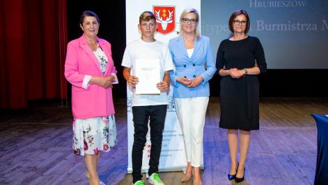Kobiety oraz stypendysta pozują do zdjęcia, w tle widać roll-up z herbem miasta Hrubieszów
