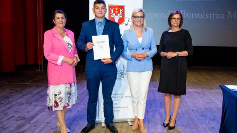 Kobiety oraz stypendysta pozują do zdjęcia, w tle widać roll-up z herbem miasta Hrubieszów
