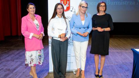 Kobiety oraz stypendystka pozują do zdjęcia, w tle widać roll-up z herbem miasta Hrubieszów