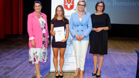 Kobiety oraz stypendystka pozują do zdjęcia, w tle widać roll-up z herbem miasta Hrubieszów