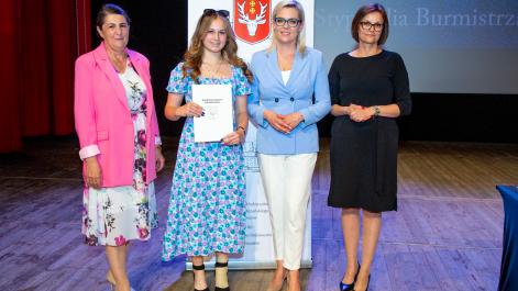 Kobiety oraz stypendystka pozują do zdjęcia, w tle widać roll-up z herbem miasta Hrubieszów