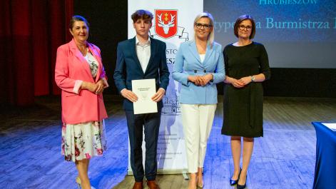Kobiety oraz stypendysta pozują do zdjęcia, w tle widać roll-up z herbem miasta Hrubieszów