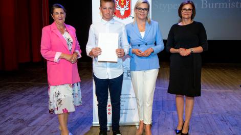 Kobiety oraz stypendysta pozują do zdjęcia, w tle widać roll-up z herbem miasta Hrubieszów