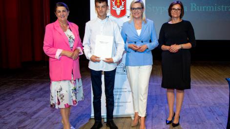 Kobiety oraz stypendysta pozują do zdjęcia, w tle widać roll-up z herbem miasta Hrubieszów