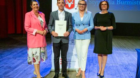 Kobiety oraz stypendysta pozują do zdjęcia, w tle widać roll-up z herbem miasta Hrubieszów