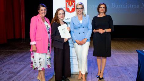 Kobiety oraz stypendystka pozują do zdjęcia, w tle widać roll-up z herbem miasta Hrubieszów
