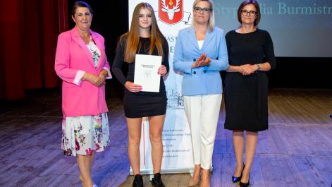 Kobiety oraz stypendystka pozują do zdjęcia, w tle widać roll-up z herbem miasta Hrubieszów