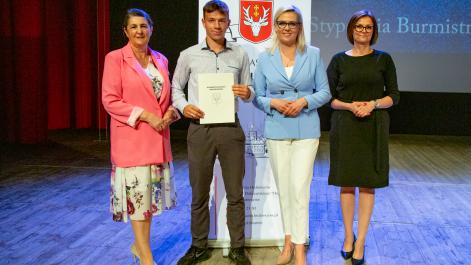 Kobiety oraz stypendysta pozują do zdjęcia, w tle widać roll-up z herbem miasta Hrubieszów