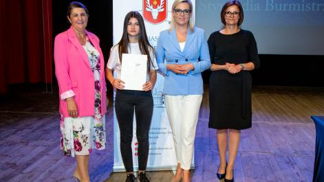 Kobiety oraz stypendystka pozują do zdjęcia, w tle widać roll-up z herbem miasta Hrubieszów
