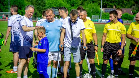 Zdjęcie grupowe zawodników, sędziów oraz niepełnosprawnego mężczyzny