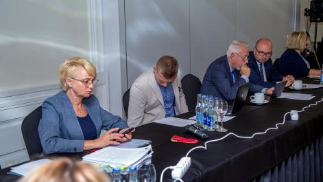 Kobieta trzyma telefon, trzech mężczyzn rozmawia
