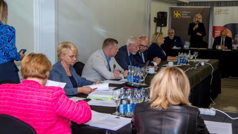 Członkowie zarządu siedzą obok siebie, biorą udział w obradach