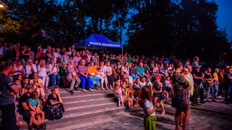 publiczność ogląda koncert, pomiędzy nimi stoi niebieski namiot z logami miasta