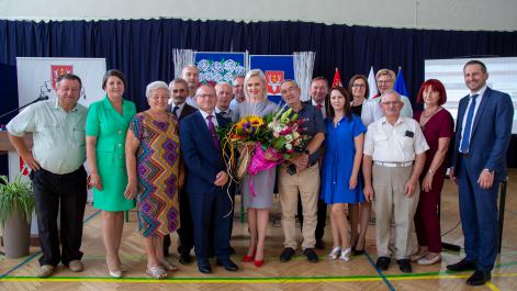 Grupa osób pozuje do zdjęcia na tle granatowej dekoracji.