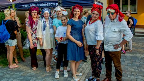 Kobiety i jeden mężczyzna mają na głowach charakterystyczne ludowe chusty