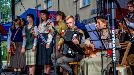 Dzieci przebrane za powstańców grają na instrumentach