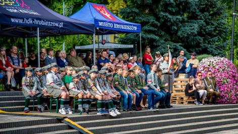 Widzowie siedzą na ławkach pod niebieskimi namiotami, oglądają część artystyczną