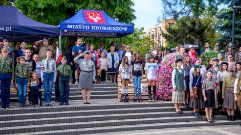 Artyści, harcerze oraz uczestnicy wydarzenia stoją na baczność, trwa wycie syren upamiętniające rozpoczęcie powstania